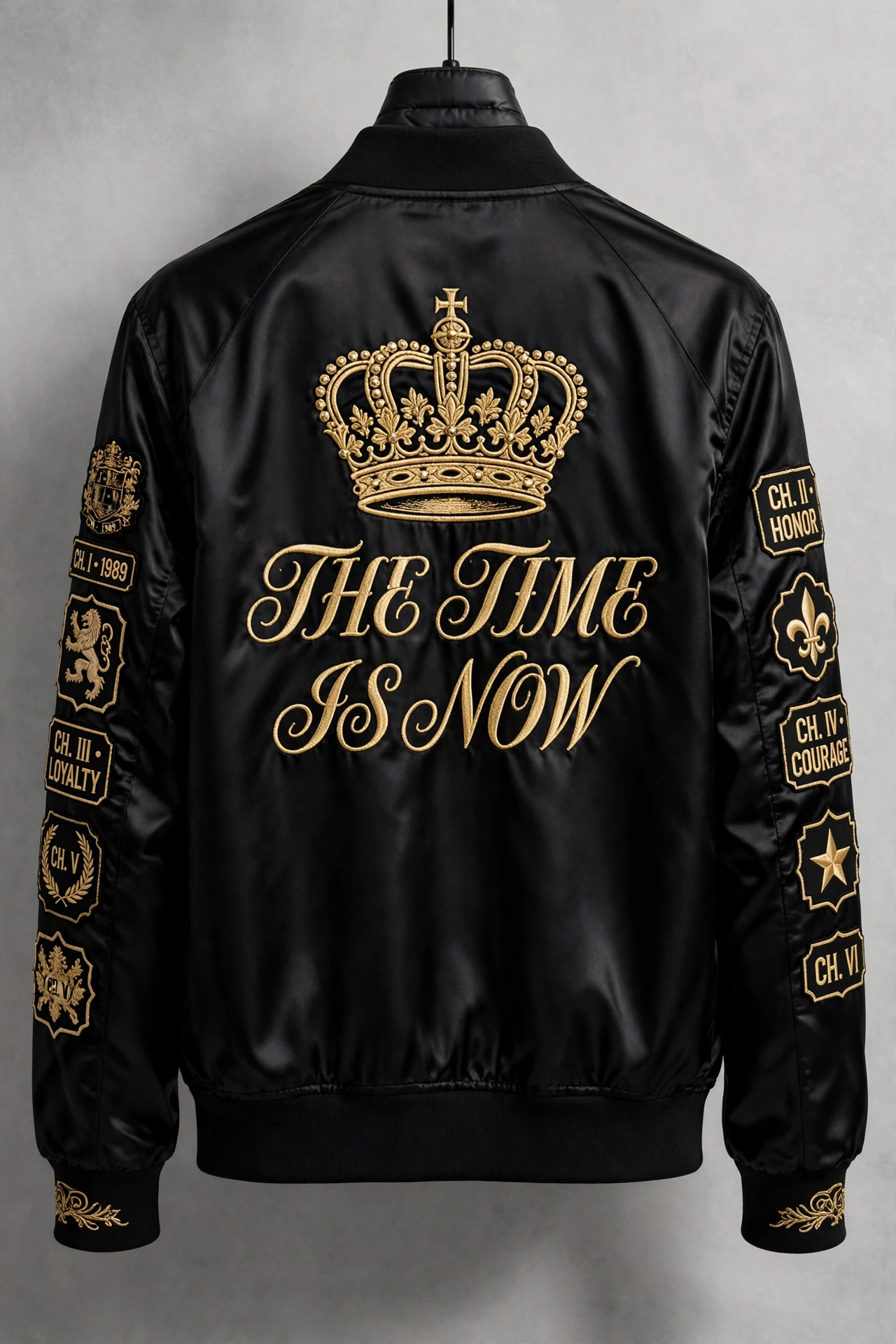 Time Is Now Heritage Tour Jacket — black satin bomber shown from the back with a giant gold embroidered crown over THE TIME IS NOW in gold script and gold chapter patches down both sleeves